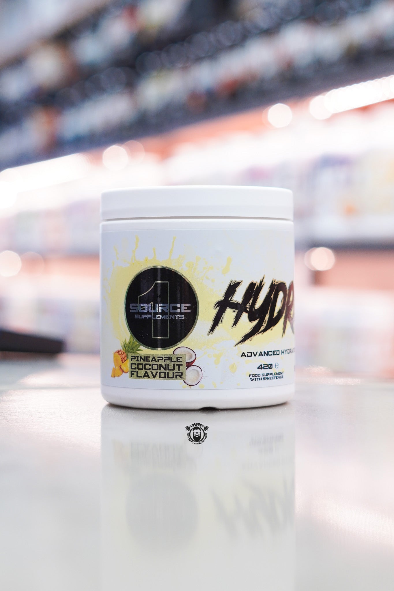 1 Source Supplements Hydrate 1 advanced hydration formula Pineapple Coconut flavour 420g tub on retail counter with blurred supplement store background