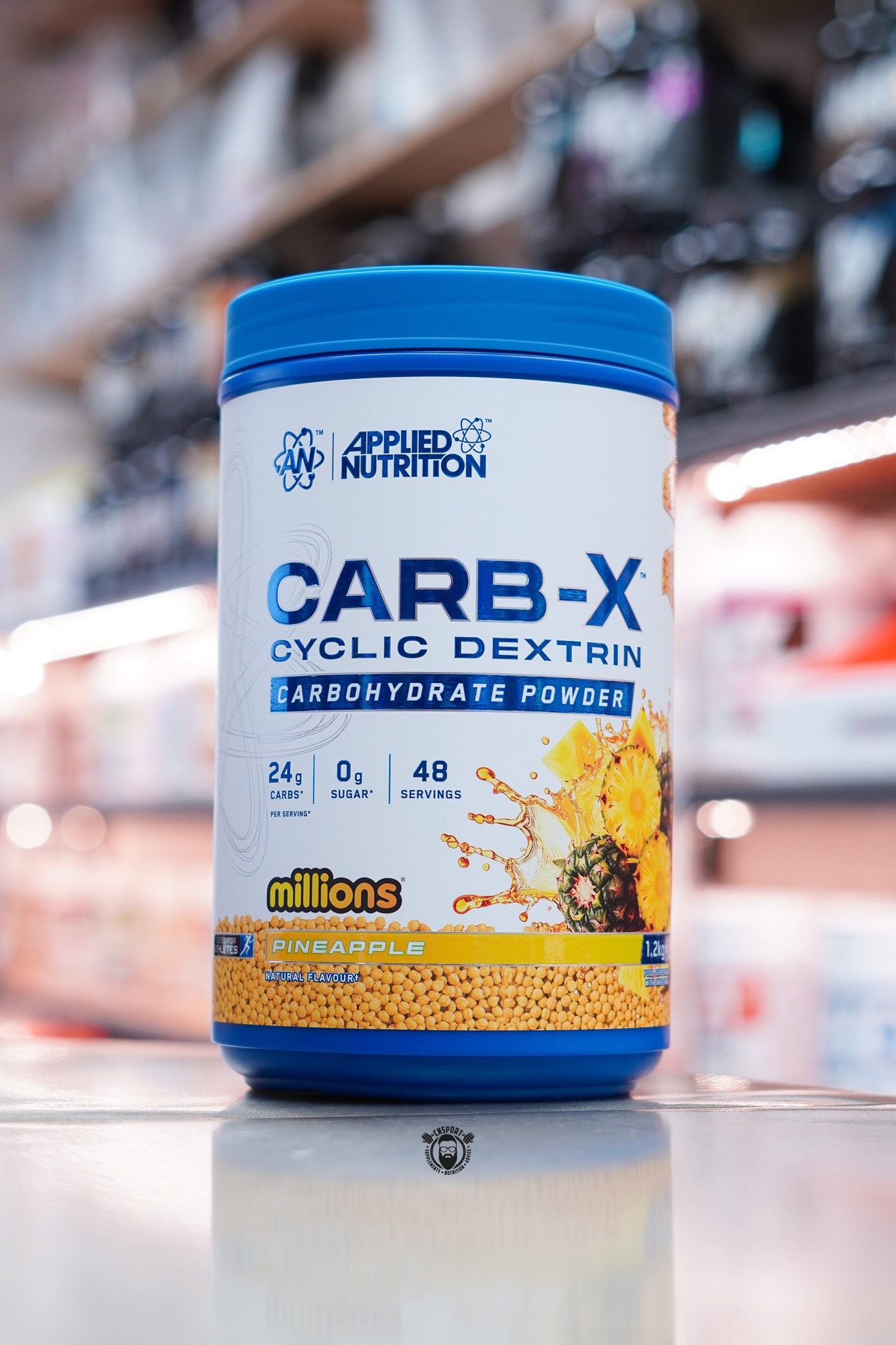 Applied Nutrition Carb-X Cyclic Dextrin carbohydrate powder, Pineapple Millions flavour, 1.2kg tub on supplement store counter.