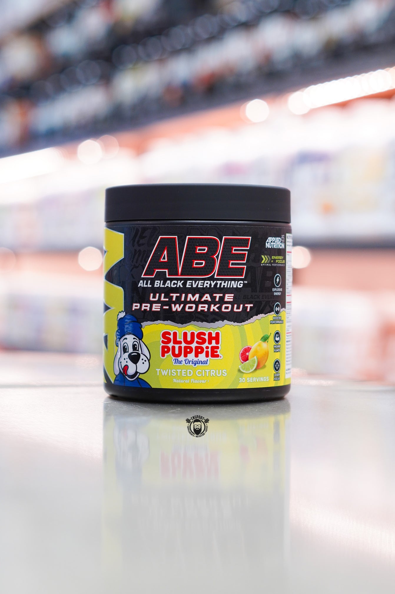 Applied Nutrition ABE All Black Everything Ultimate Pre-Workout in Twisted Citrus Slush Puppie flavour on retail counter with blurred supplement store background