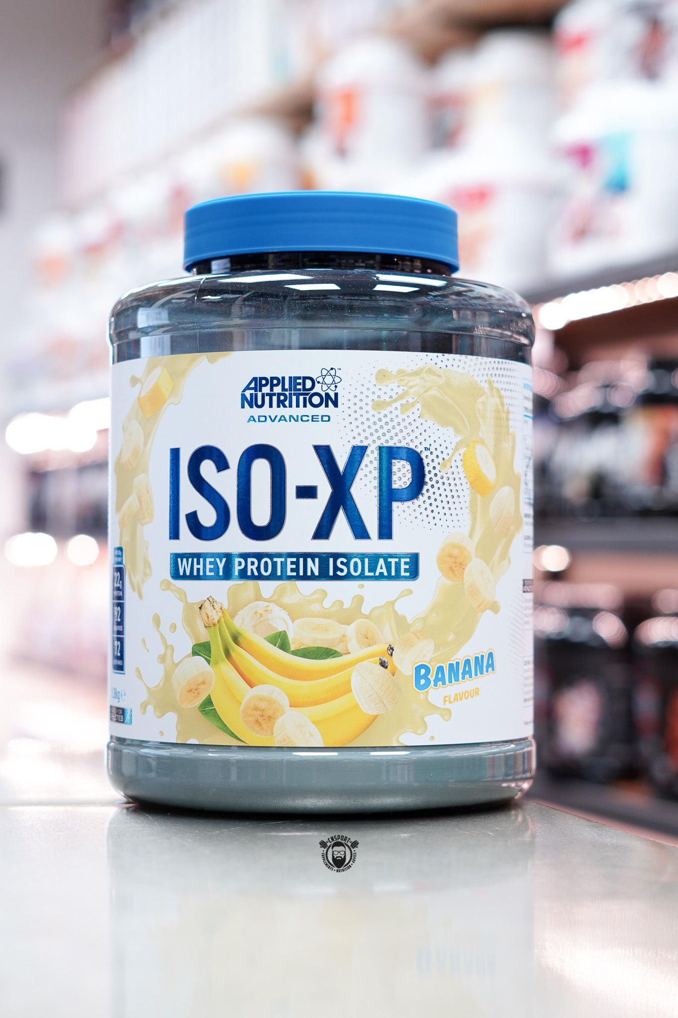Applied Nutrition ISO-XP Whey Protein Isolate container with banana flavor on a blurred store shelf background