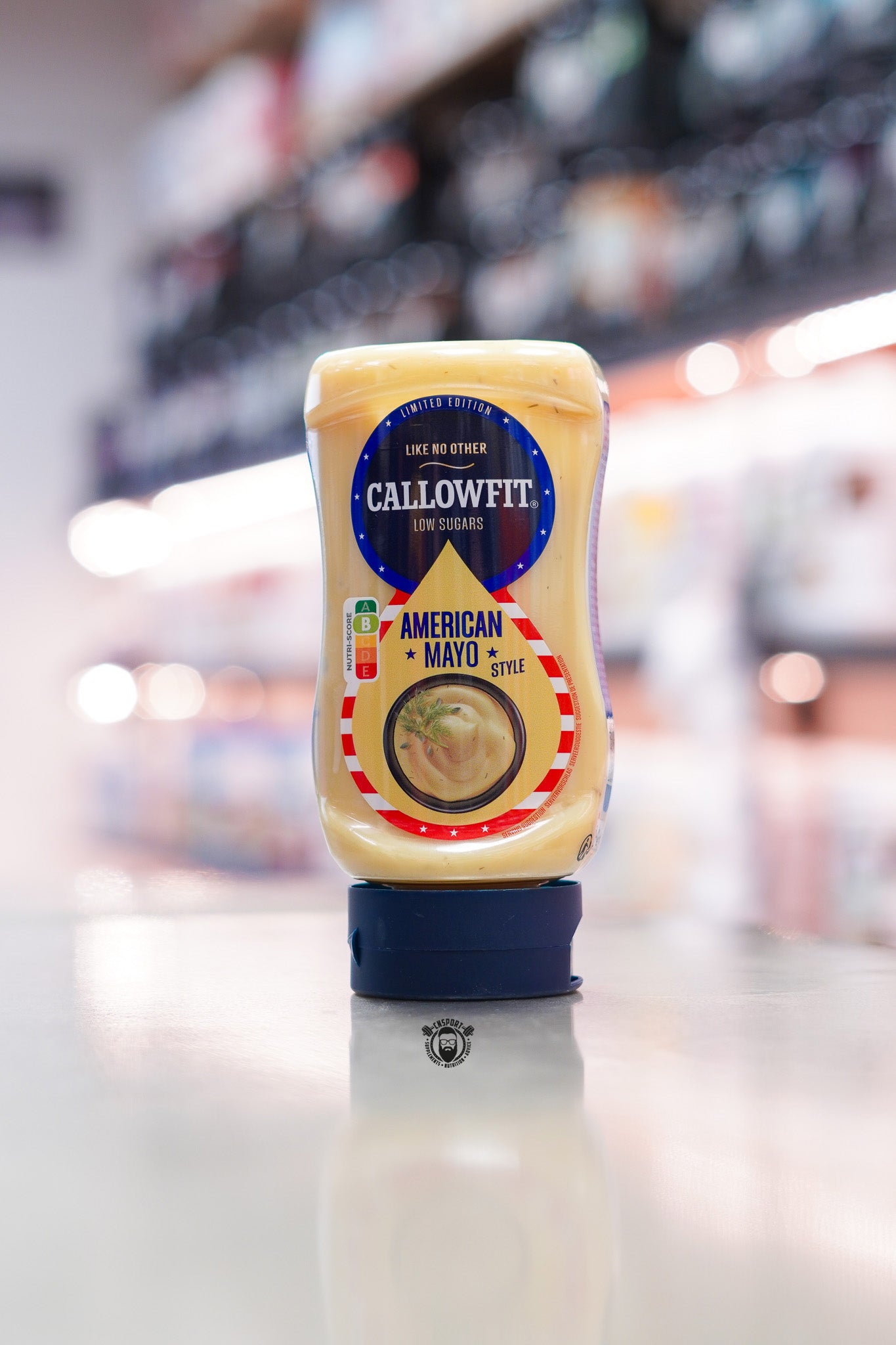 Callowfit American Mayo Style low sugar sauce bottle, limited edition packaging with Nutri-Score B, displayed upright on a countertop in a supplement store.