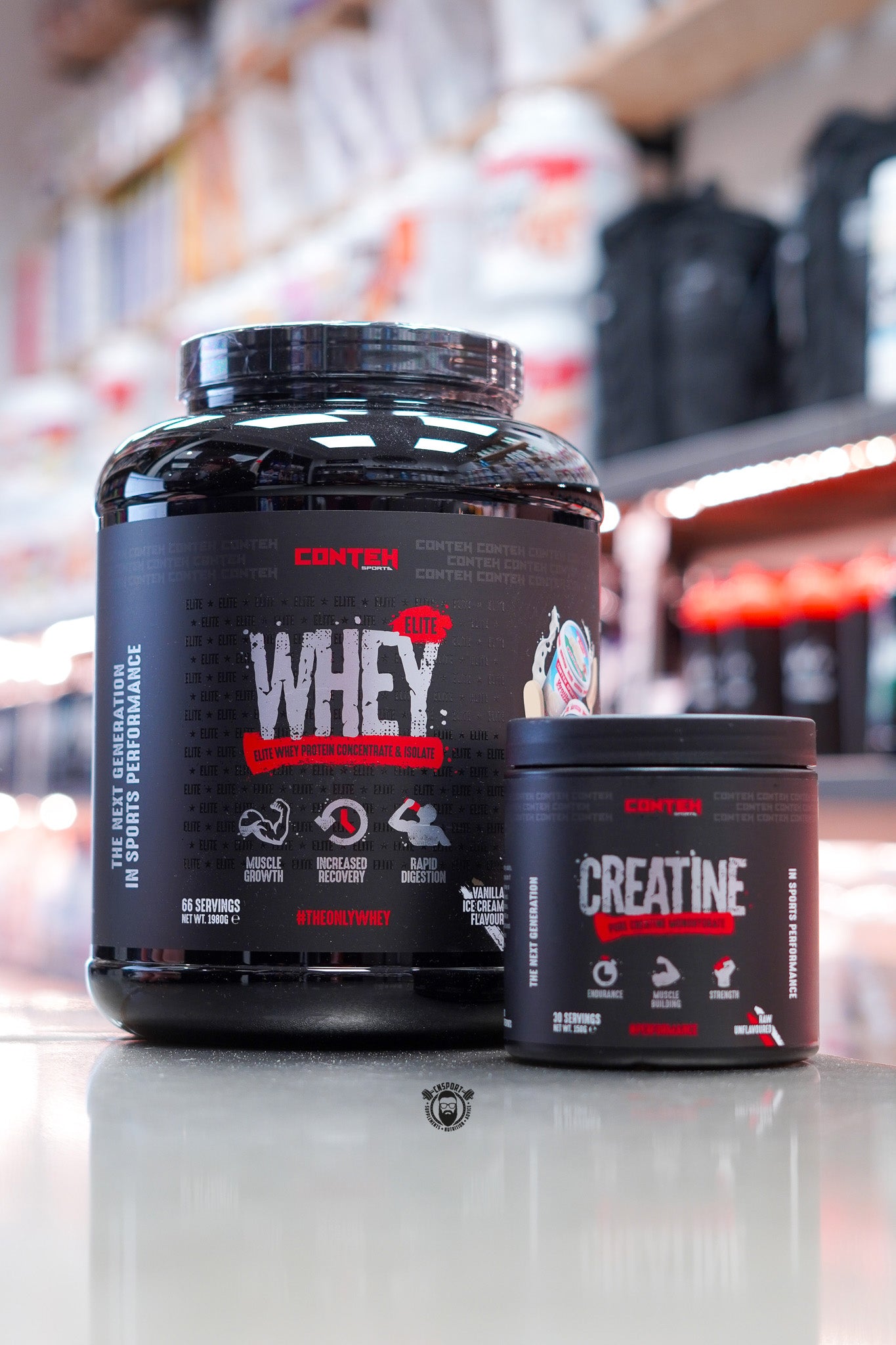 Conteh Elite Whey protein (Vanilla Ice Cream flavour) 1.98kg tub alongside Conteh Creatine monohydrate 30 serving tub, black and red labels, displayed on counter in supplement store.