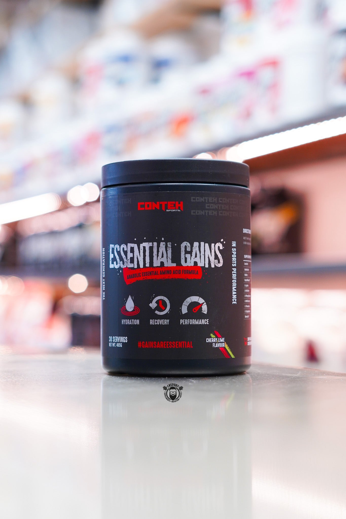 Conteh Sports Essential Gains amino acid formula tub, Cherry Lime flavour, displayed on supplement store counter.