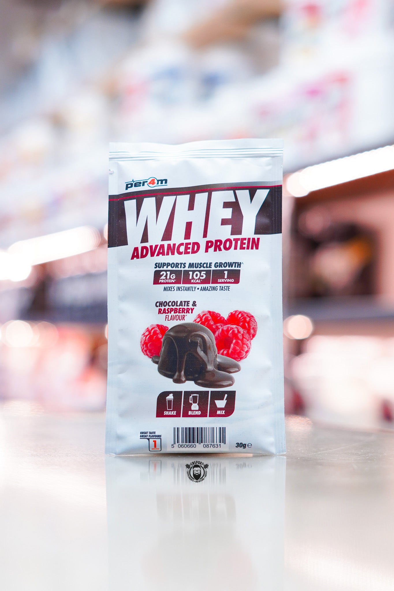 Per4m Advanced Whey Protein sample sachet, Chocolate & Raspberry flavour, displayed on supplement store counter.