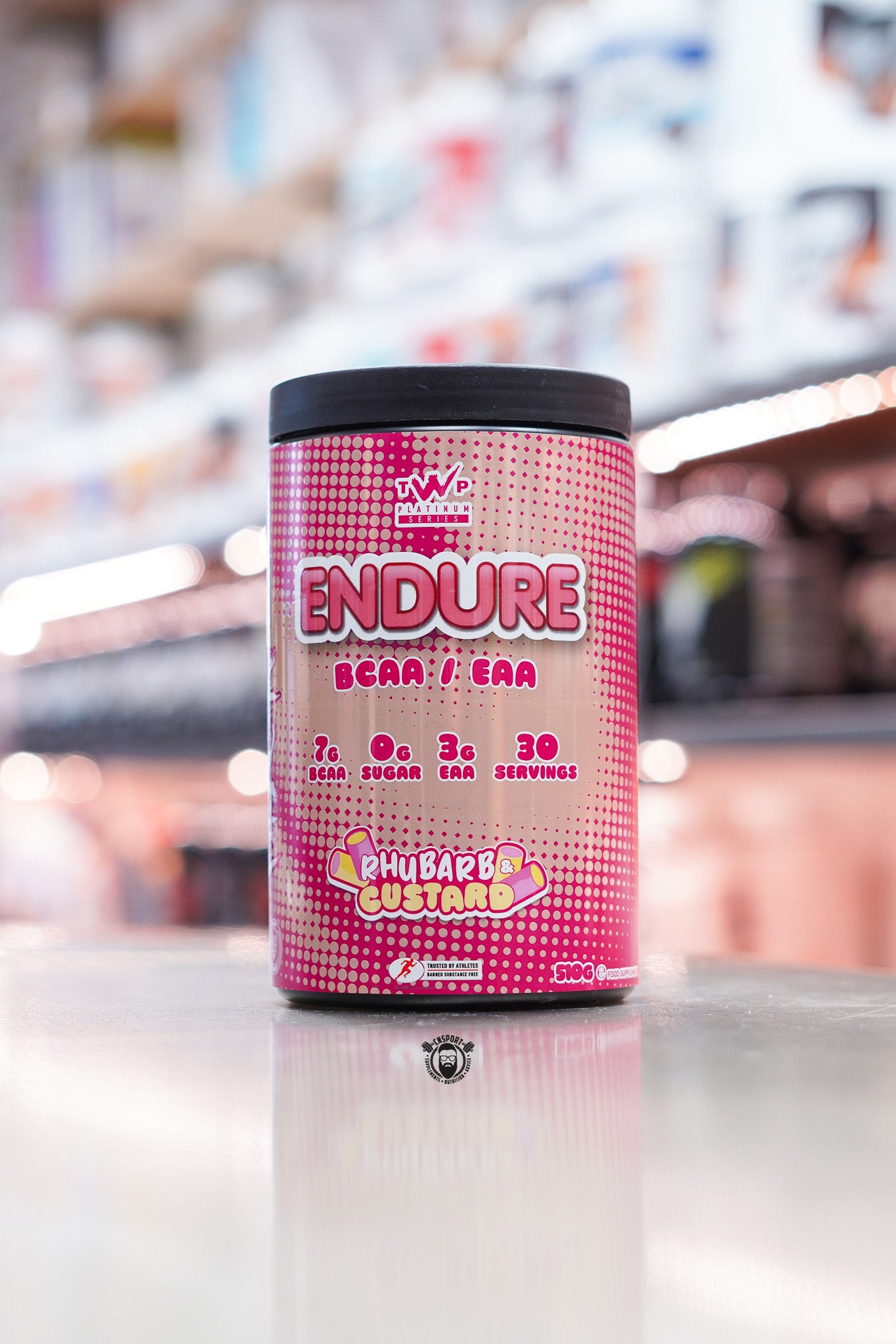TWP Platinum Series Endure BCAA / EAA supplement, Rhubarb & Custard flavour, 510g tub, displayed on supplement store counter.