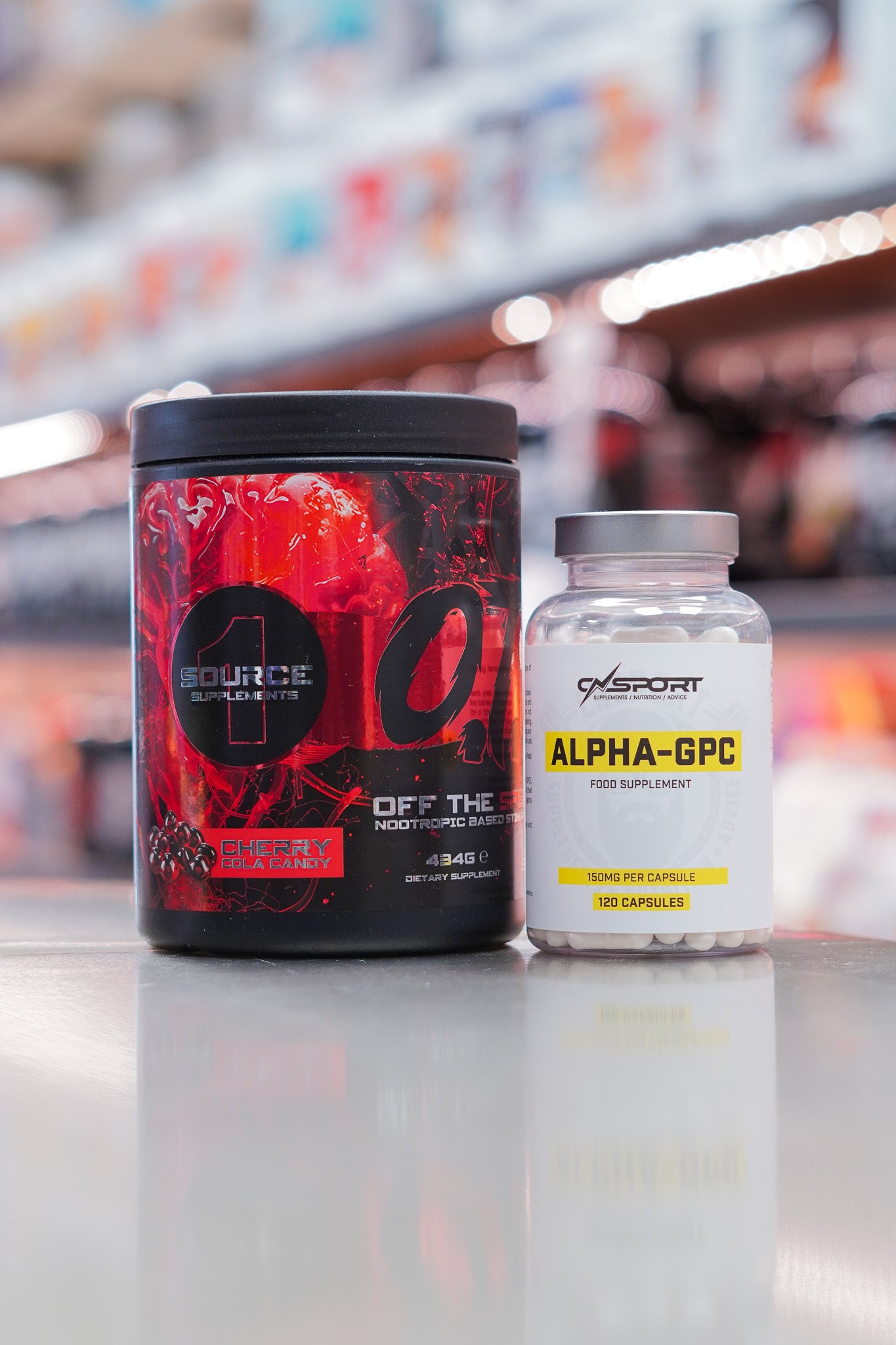 1 Source Supplements OTS pre-workout Cherry Cola Candy flavour (434g) with CNSport Alpha-GPC 150mg capsules (120 capsules) displayed on supplement store counter.