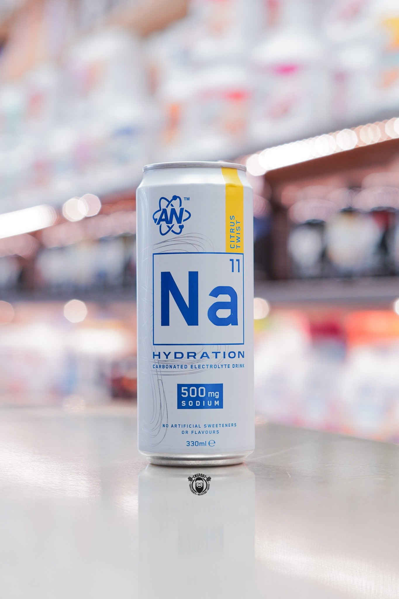Applied Nutrition Na11 Hydration can Citrus Twist flavour, front view on reflective surface with blurred supplement store background