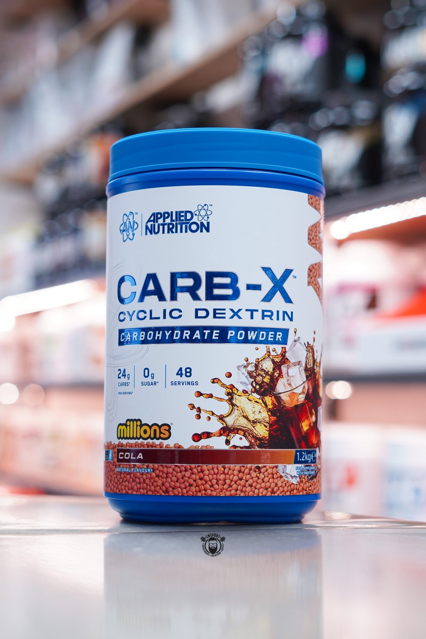 Applied Nutrition Carb-X Cyclic Dextrin carbohydrate powder, Cola Millions flavour, 1.2kg tub on supplement store counter.