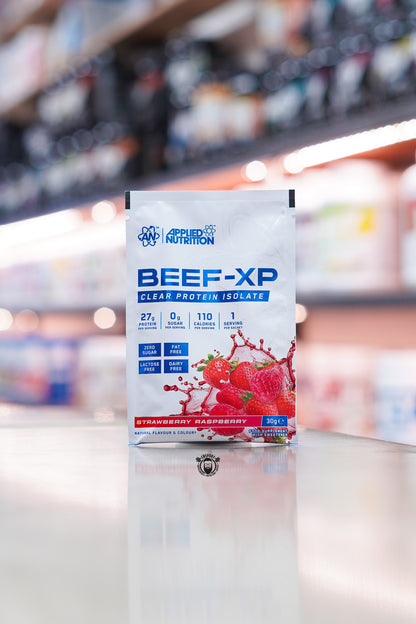 Applied Nutrition Beef-XP Clear Protein Isolate Strawberry Raspberry flavour 30g single serving sachet displayed on a supplement shop counter.