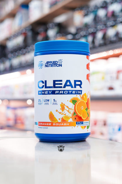 Applied Nutrition Clear Whey Protein Orange Squash flavour 875g tub with 21g protein per serving displayed on a supplement shop counter.