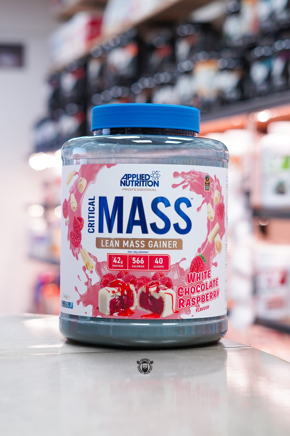 Applied Nutrition Critical Mass Professional lean mass gainer, White Chocolate Raspberry flavour, 2.4kg tub displayed on a supplement store counter.