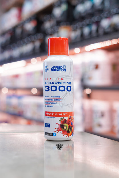 Applied Nutrition L-Carnitine Liquid 3000 Fruit Burst flavour bottle, 480ml with 32 servings, displayed on a supplement shop counter.
