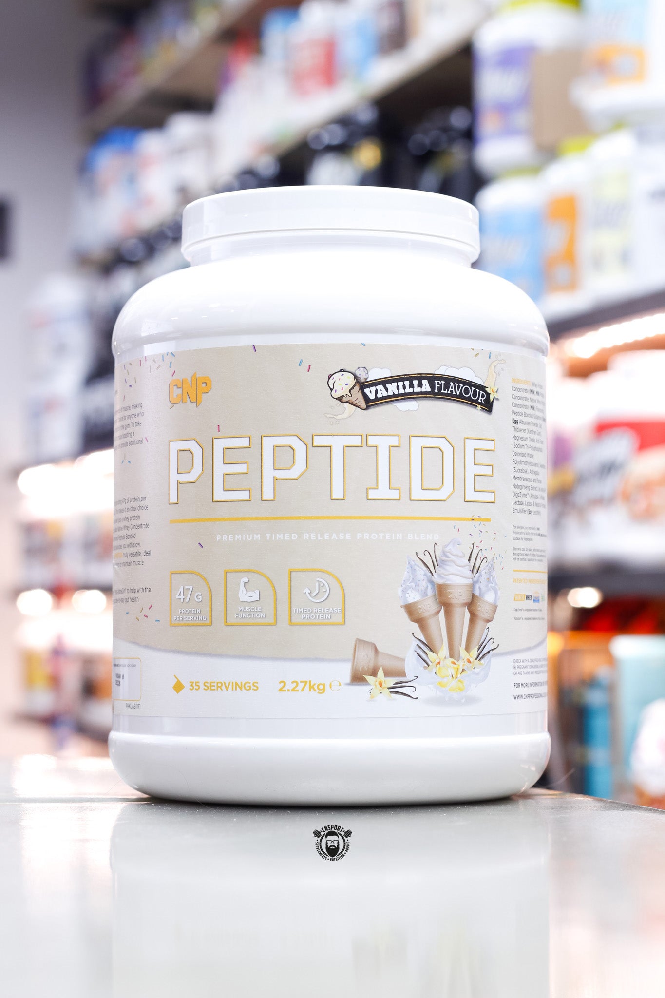 Vanilla Flavour CNP Peptide timed release protein blend in a 2.27kg tub, with a cream-coloured label featuring vanilla flowers and ice cream cones, offering 47g protein per serving across 35 servings.