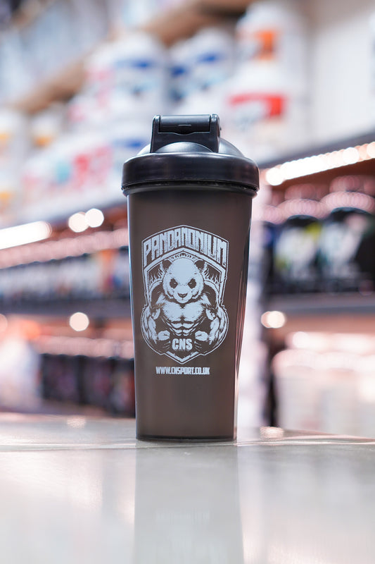 CNSport Pandamonium 600ml black shaker bottle with flip cap closed, featuring panda logo branding, placed on a counter with blurred supplement shelves in the background.