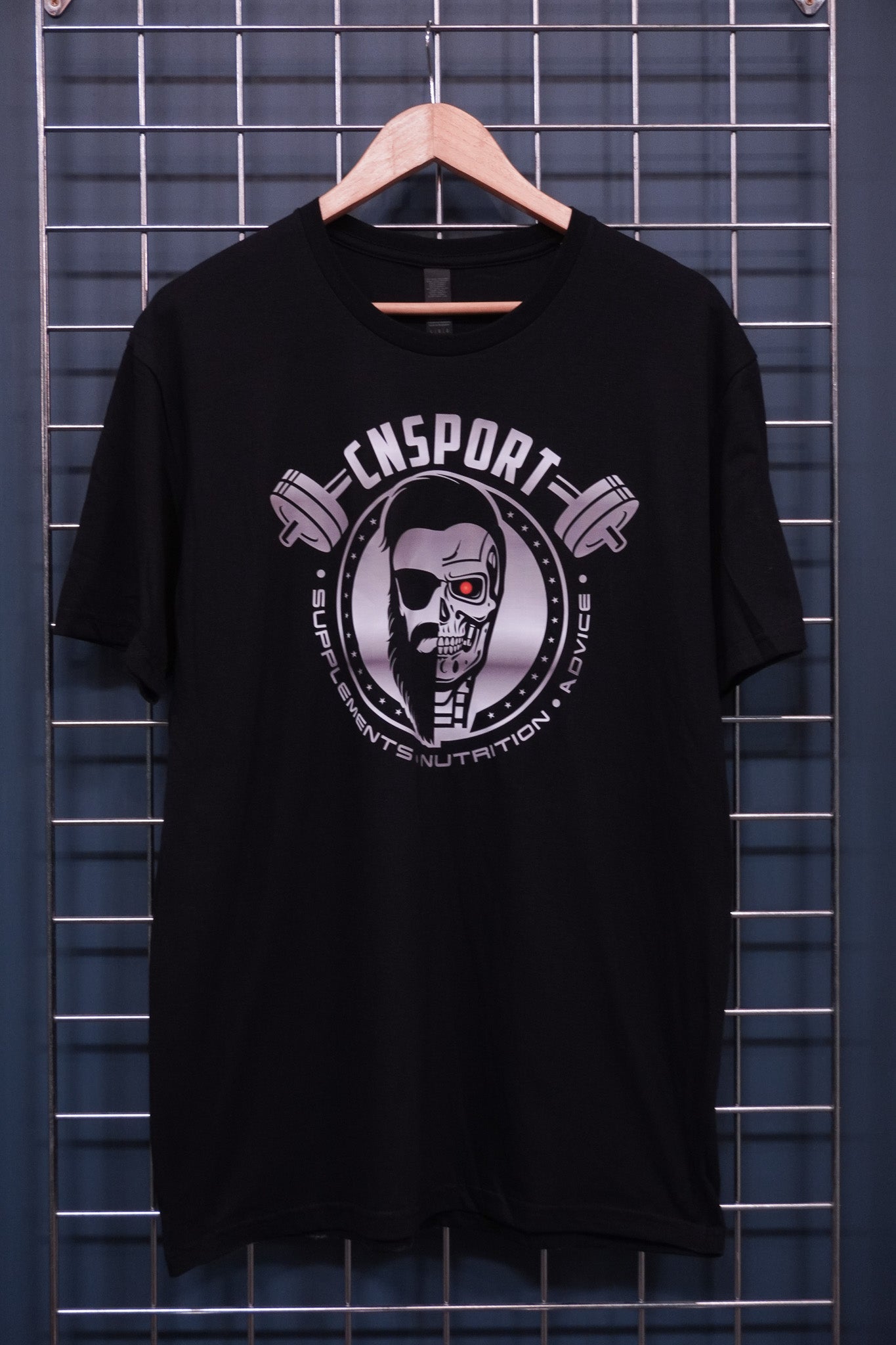 Full front view of black CNSport Terminator T-shirt hanging on metal grid display wall with large chest graphic design