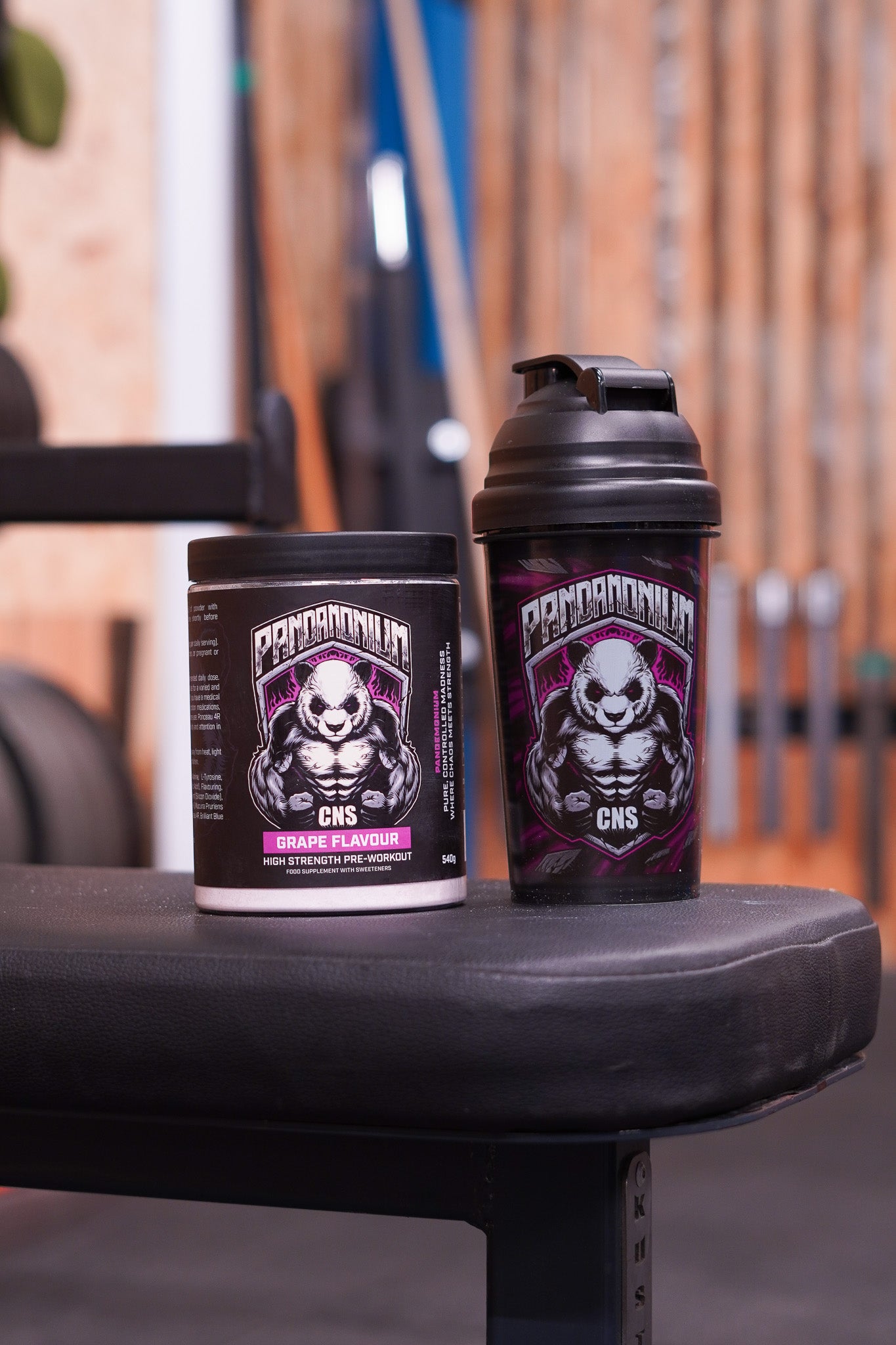 CNSport Pandamonium Grape Pre-Workout tub sitting on a gym bench next to a black Pandamonium shaker with the signature panda mascot design.