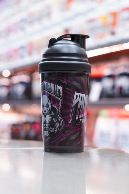 Angled view of the Pandamonium shaker highlighting the muscular panda mascot graphic and the bold purple design elements, sitting on a reflective counter with blurred supplement tubs behind.