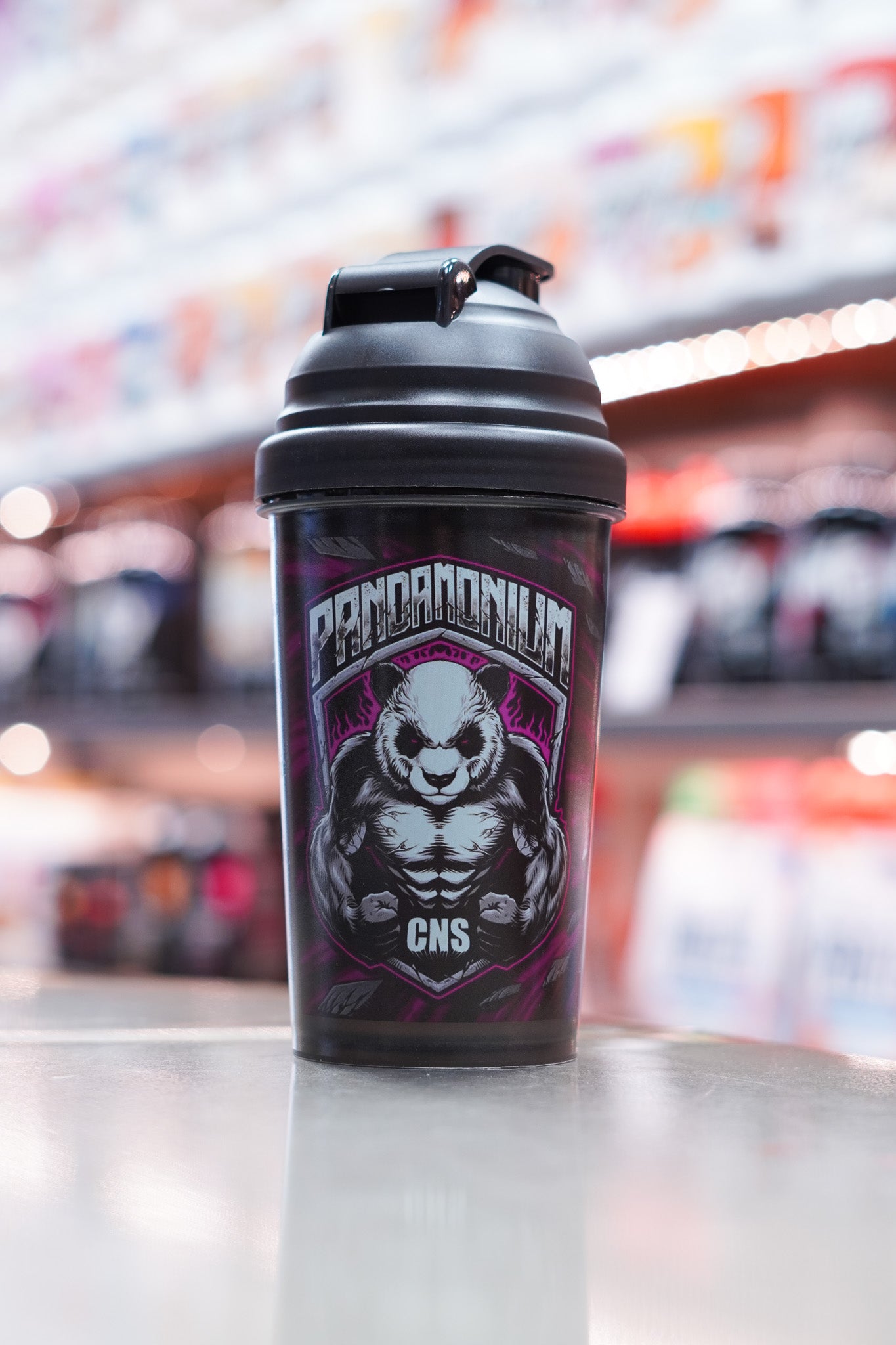 Full front shot of the CNSport Pandamonium shaker showing the detailed panda mascot artwork and bold branding, photographed indoors with bright bokeh lighting.