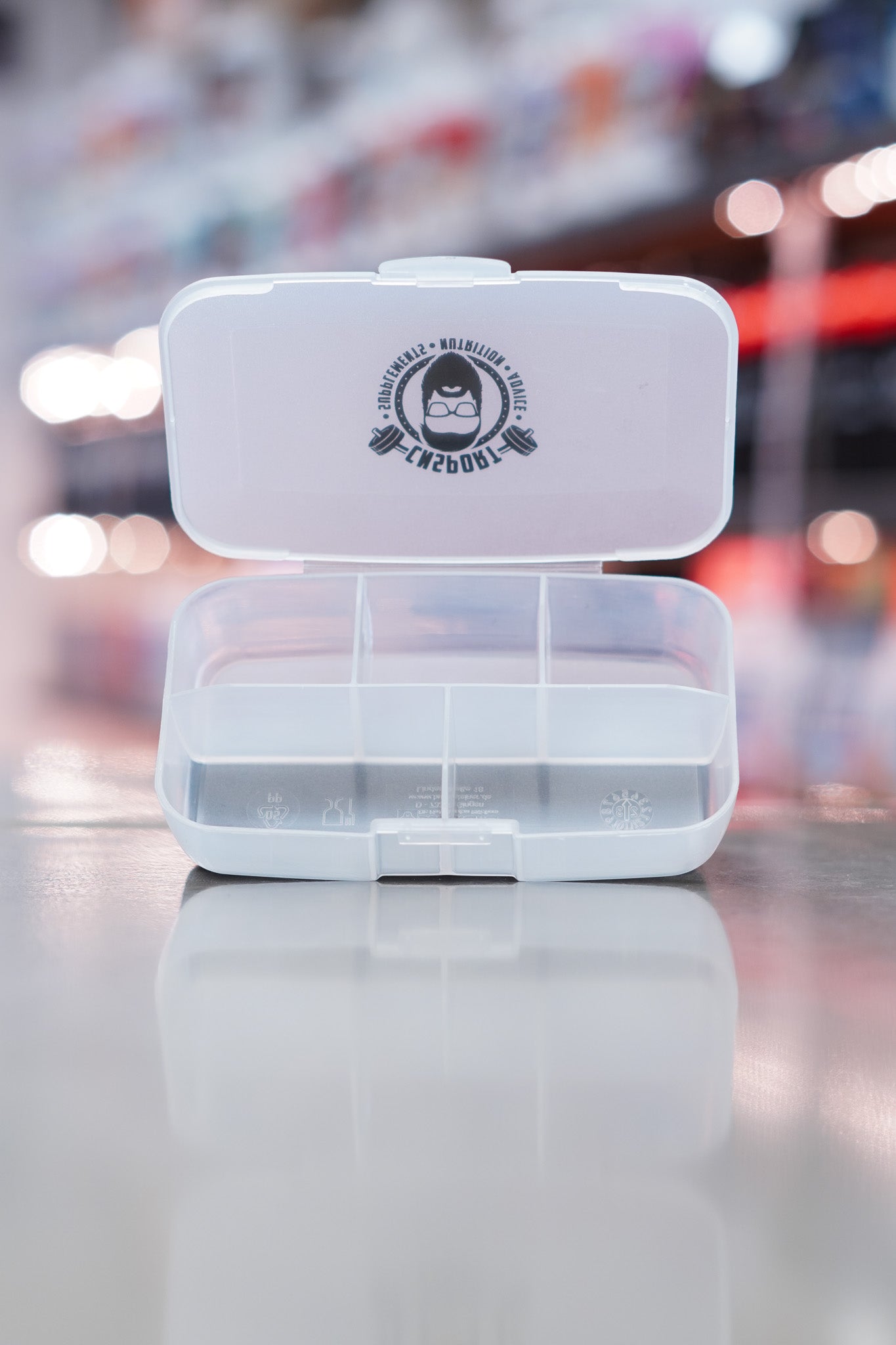 Open CNSport clear pill box with five divided compartments and visible CNSport logo printed on the outside of the lid.