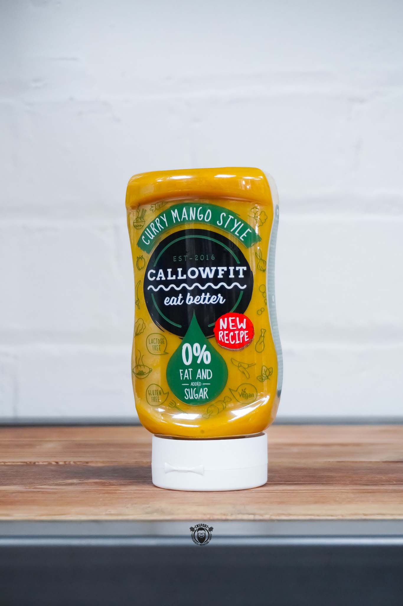 Callowfit Curry Mango Style Sauce 300ml bottle with new recipe label, 0% fat and added sugar branding, displayed on a wooden countertop.