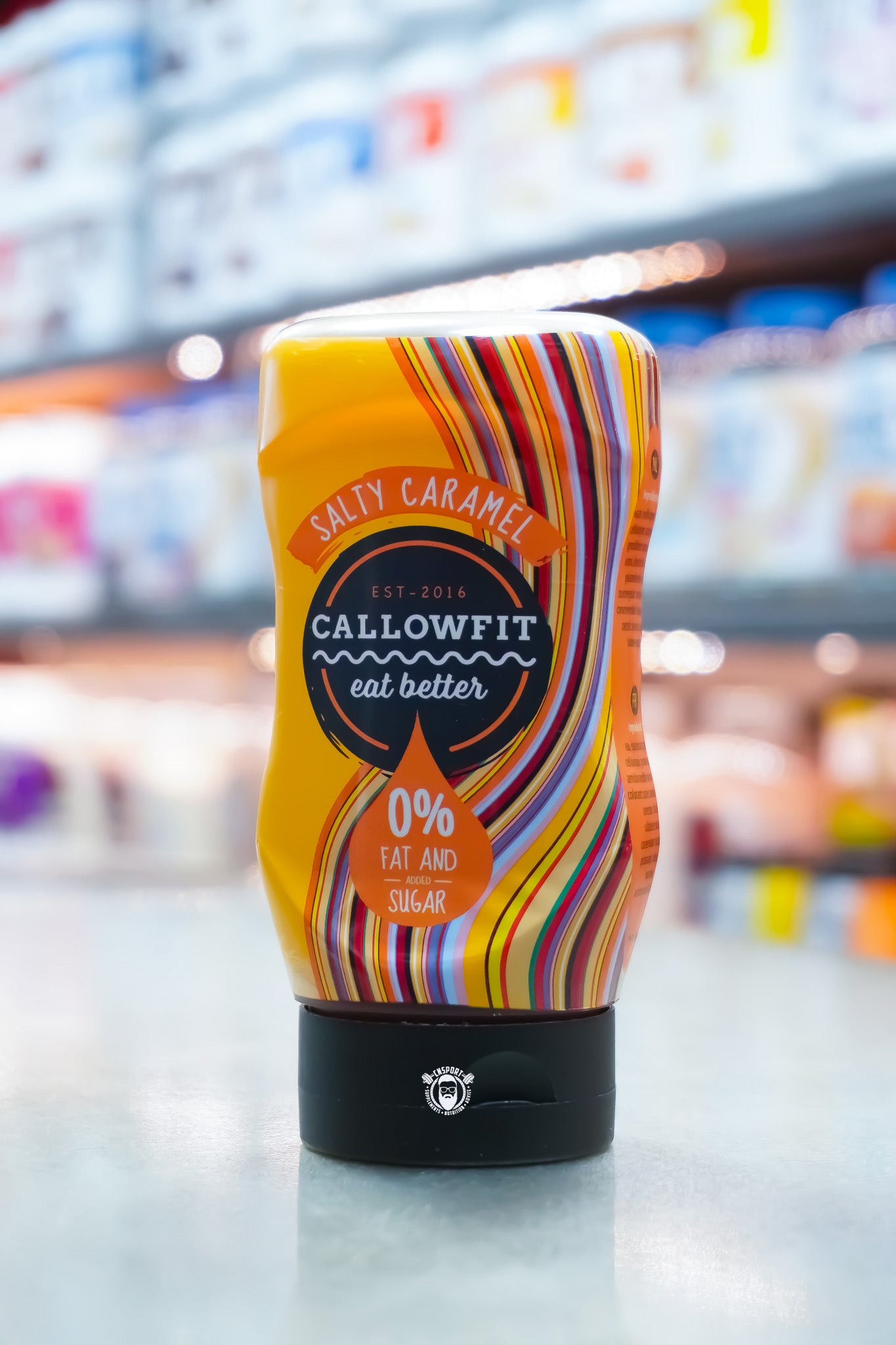 Callowfit Salty Caramel Sauce 300ml bottle with colourful striped label, sugar-free, 0% fat and vegan-friendly, displayed in a supplement store.