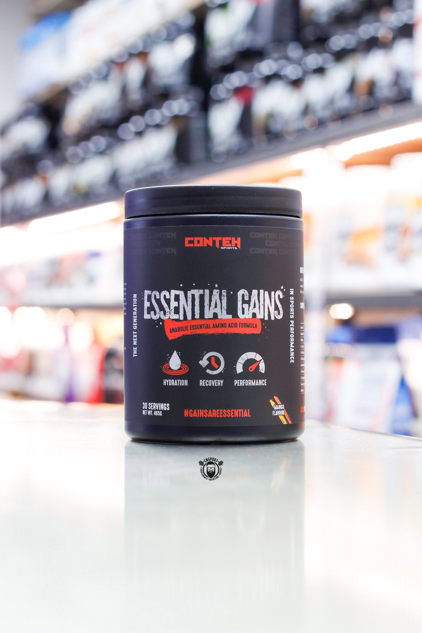 Conteh Sports Essential Gains EAA powder, mango flavour, 30 servings, black tub on supplement store counter.