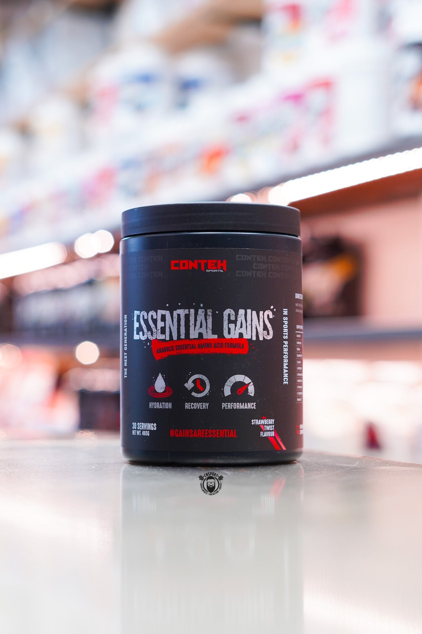 Conteh Sports Essential Gains amino acid formula tub, Strawberry Twist flavour, displayed on supplement store counter.