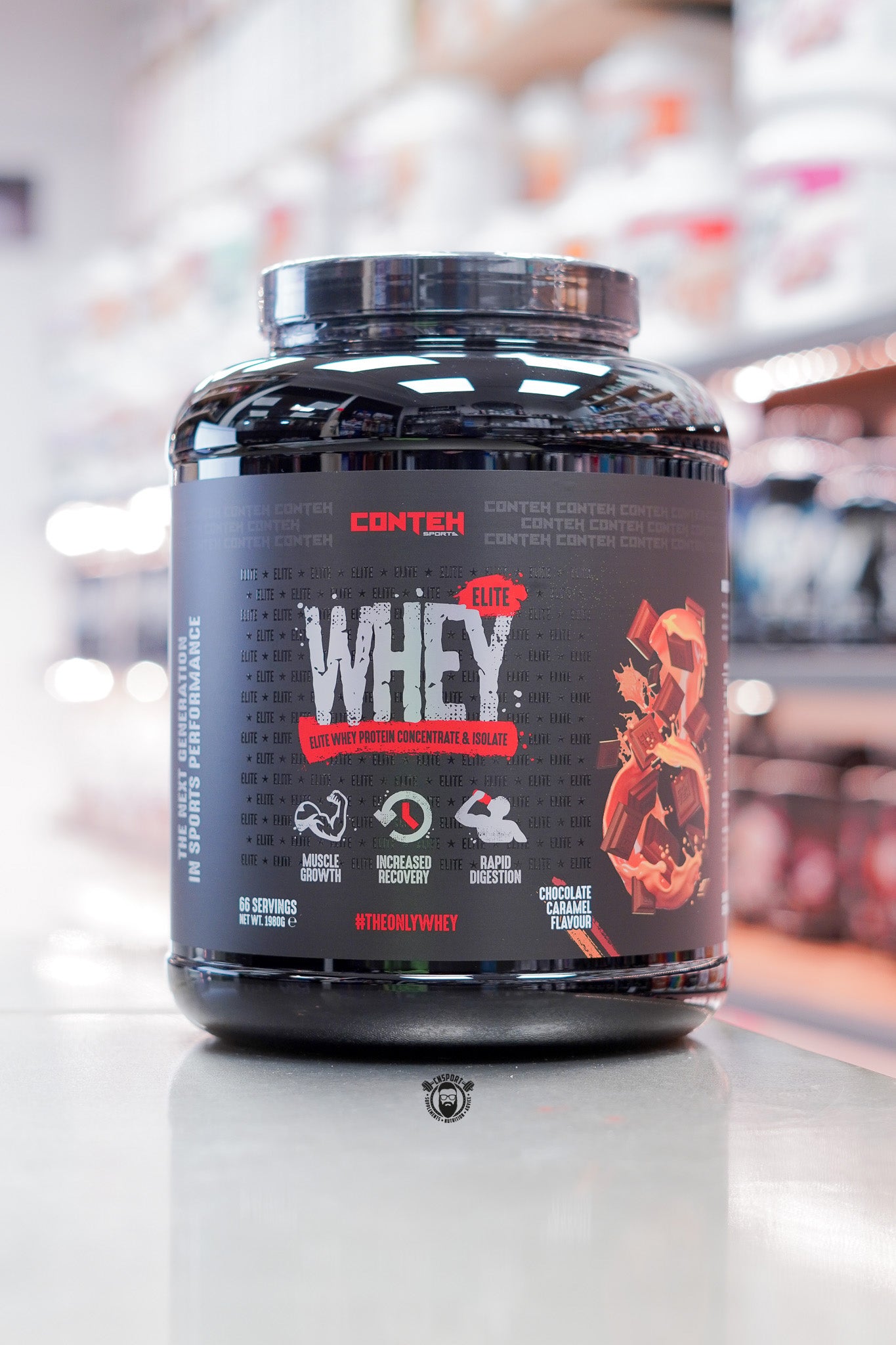 Conteh Sports Whey Elite protein powder, Chocolate Caramel flavour, 66 servings (1.98kg) black tub displayed on supplement store counter.