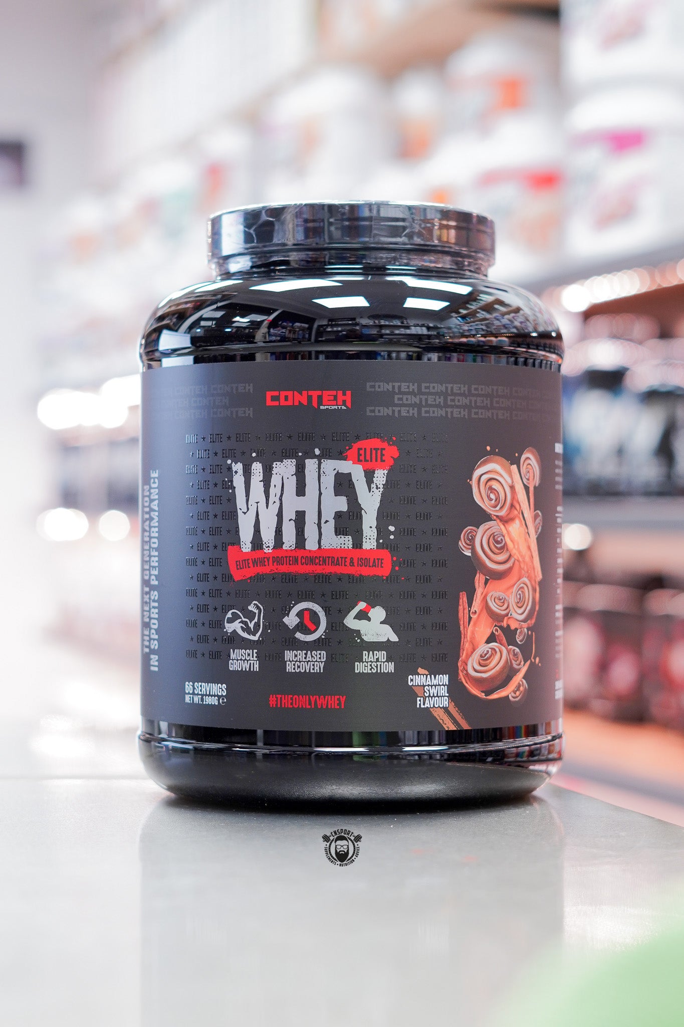 Conteh Sports Whey Elite protein powder, Cinnamon Swirl flavour, 66 servings (1.98kg) black tub displayed on supplement store counter.