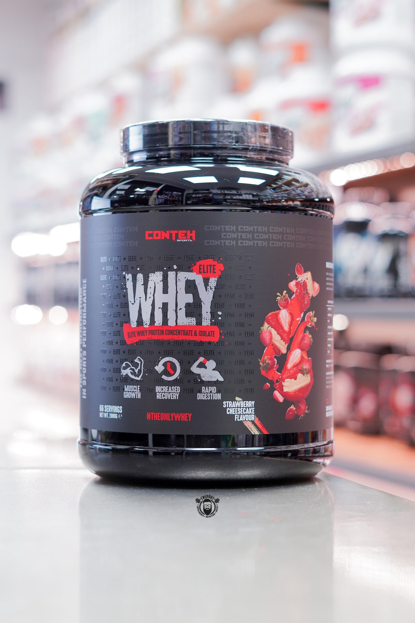Conteh Sports Whey Elite protein powder, Strawberry Cheesecake flavour, 66 servings (1.98kg) black tub displayed on supplement store counter.
