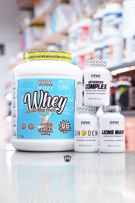 DNA Sports supplement bundle including Whey Advanced Whey Protein Cereal Milk 2kg, Artichoke Complex, Shoden Ashwagandha, and Lions Mane capsules displayed on supplement store counter.