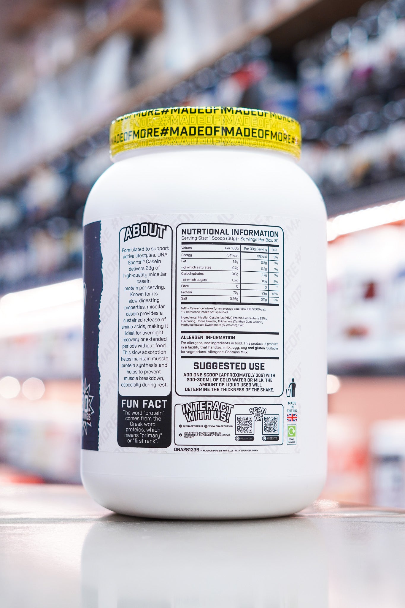DNA Sports Casein Micellar Casein Protein Chocolate Milkshake nutritional panel and supplement facts label on retail counter with blurred supplement store background