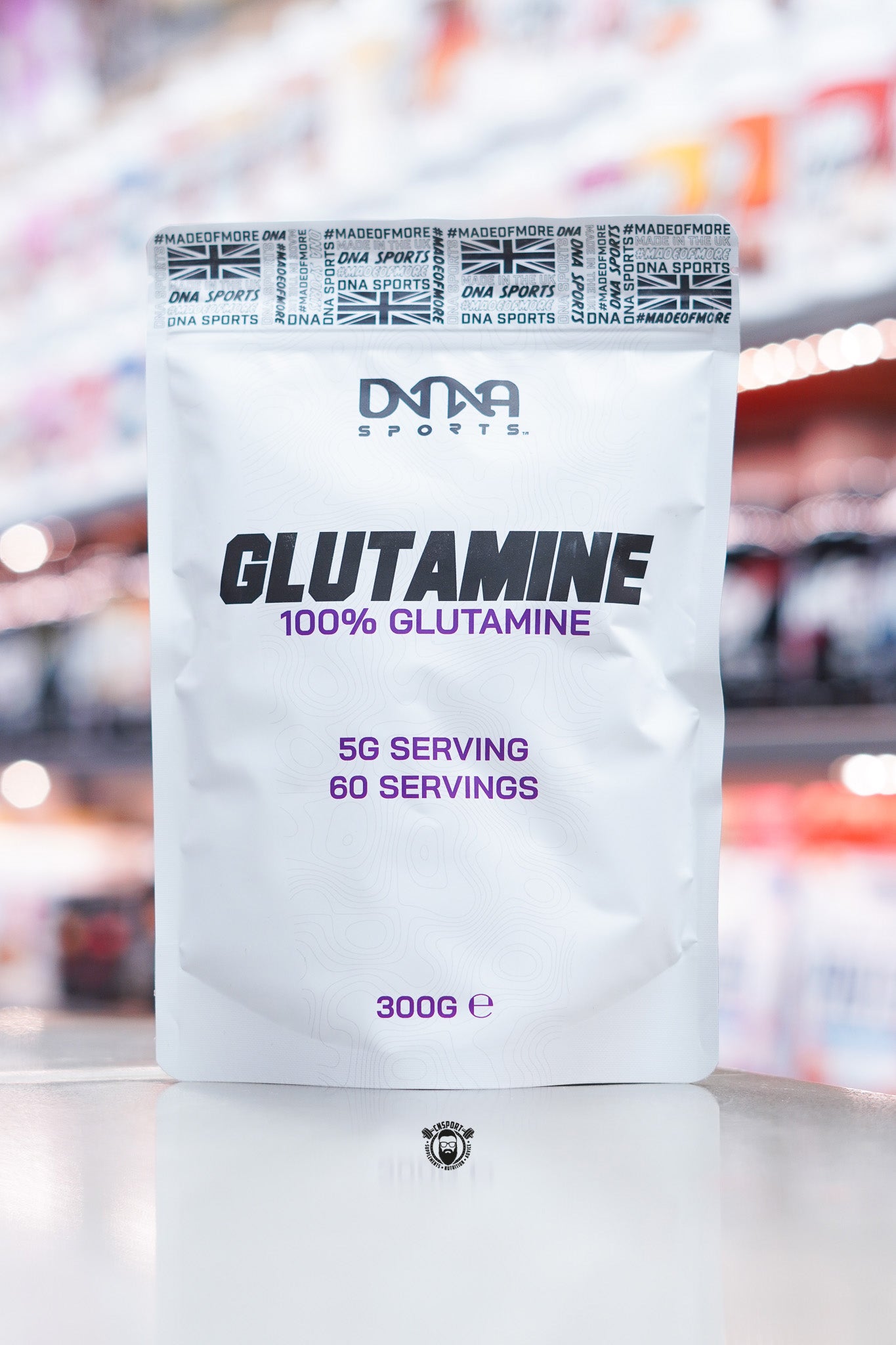Front of a DNA Sports Glutamine 300g pouch with a clean white design, DNA Sports logo, ‘Glutamine 100% Glutamine’ text in bold black and purple lettering, and serving details stating 5g per serving and 60 servings.