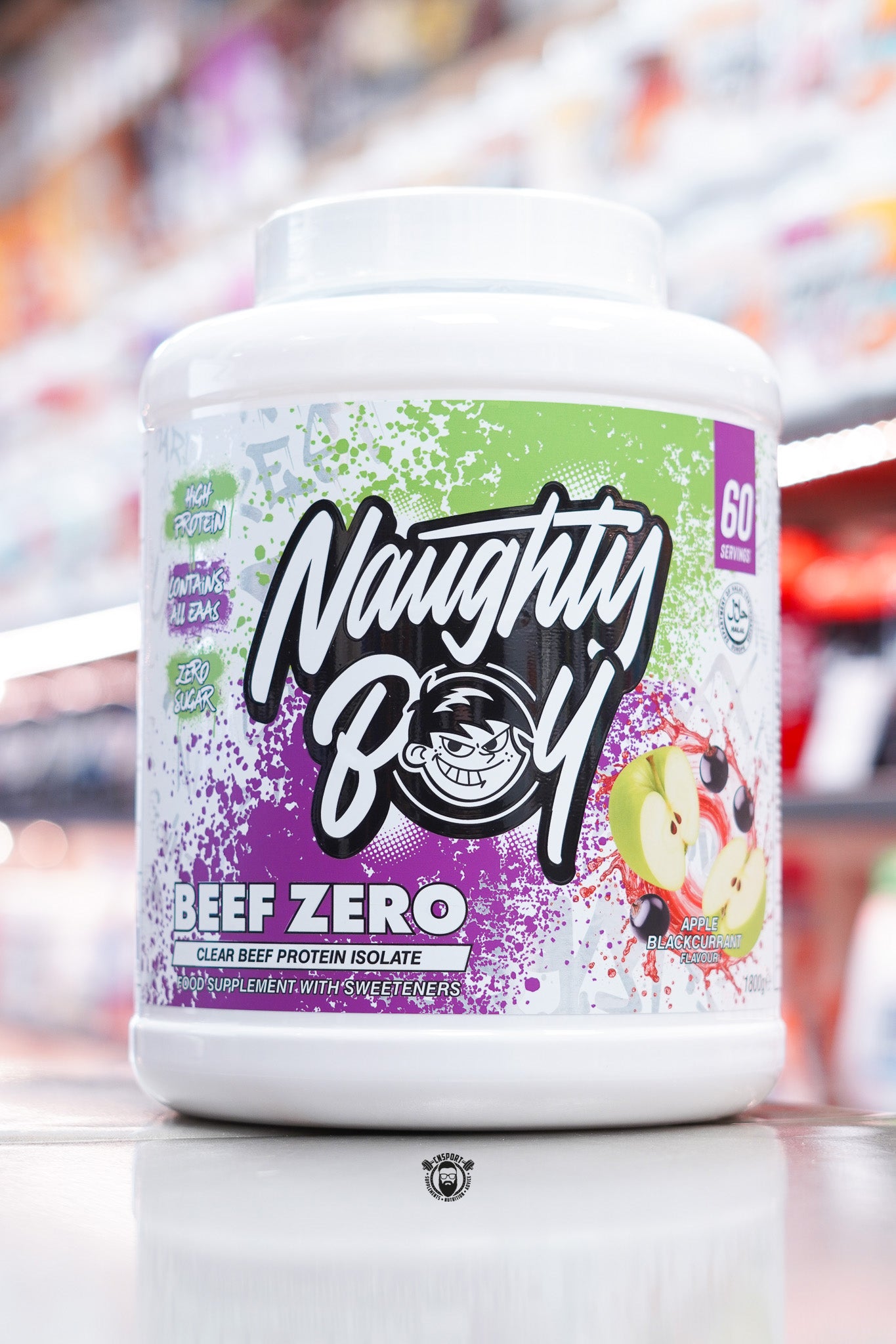 A large white tub of Naughty Boy Beef Zero clear beef protein isolate in Apple Blackcurrant flavour, featuring a green and purple splatter design with images of apples and blackcurrants on the label.