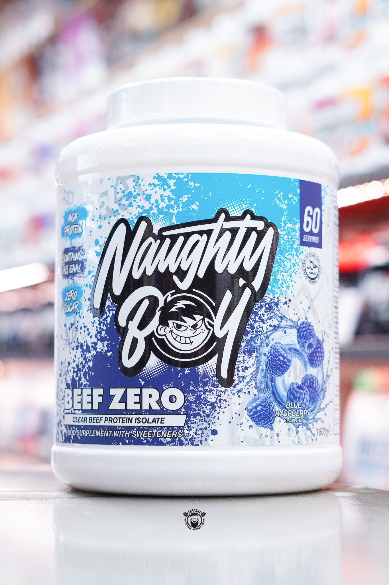 A large white tub of Naughty Boy Beef Zero clear beef protein isolate in Blue Raspberry flavour, with a blue splatter label design and images of blue raspberries on the front.