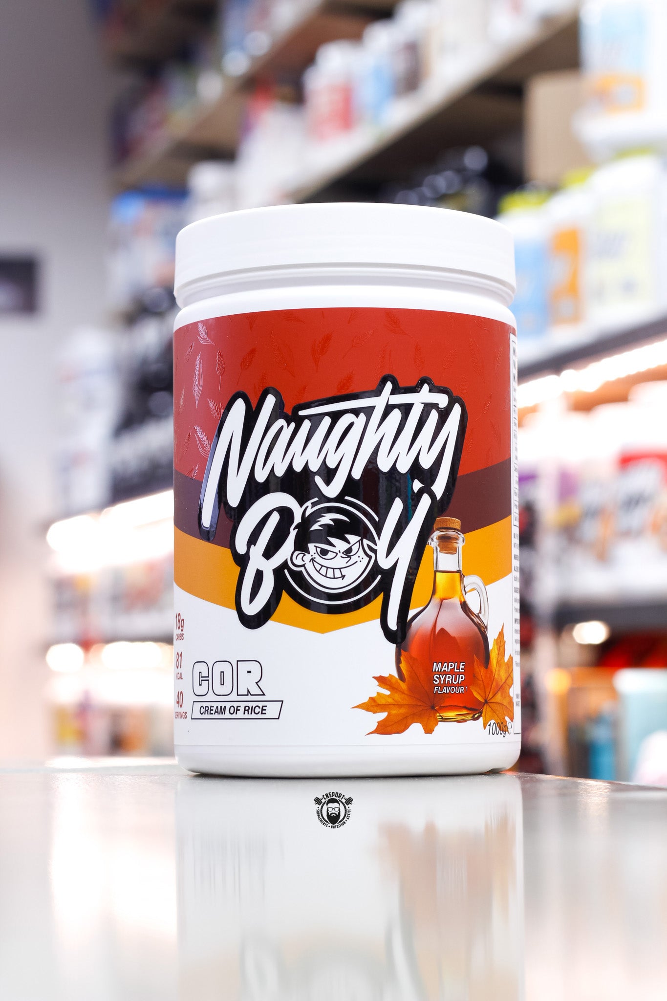 1kg Naughty Boy COR Cream of Rice in Maple Syrup flavour, with a red and amber label featuring a syrup bottle and autumn maple leaf design.