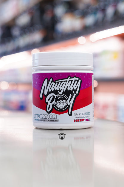 Naughty Boy Hydration Cherry Razz electrolyte drink mix tub displayed on a supplement store counter.