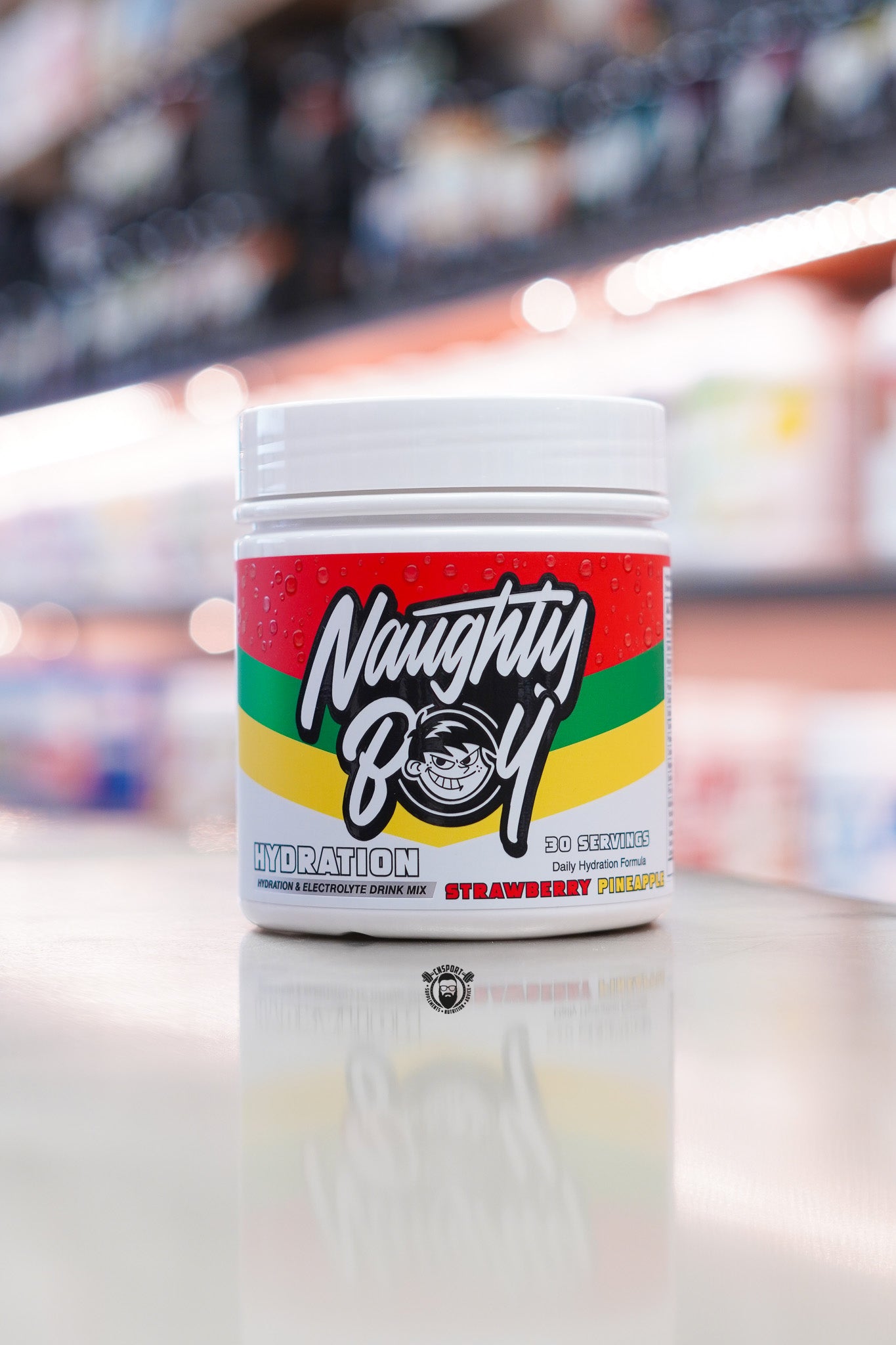 Naughty Boy Hydration Strawberry Pineapple electrolyte drink mix tub displayed on a supplement store counter.