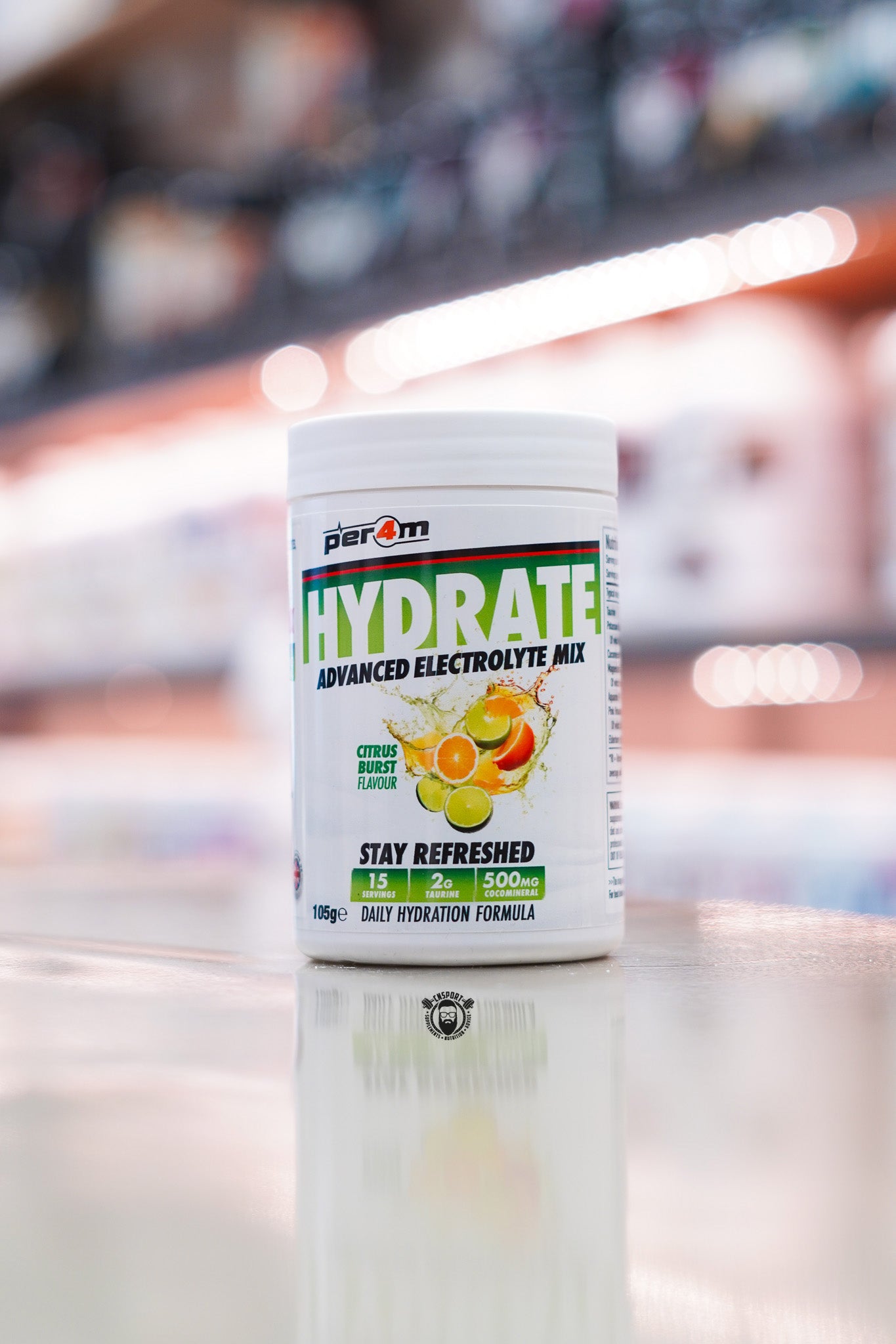 Per4m Hydrate Advanced Electrolyte Mix in Citrus Burst flavour, featuring 2g taurine, CocoMineral®, 15 servings and a daily hydration formula, displayed on a supplement store counter.