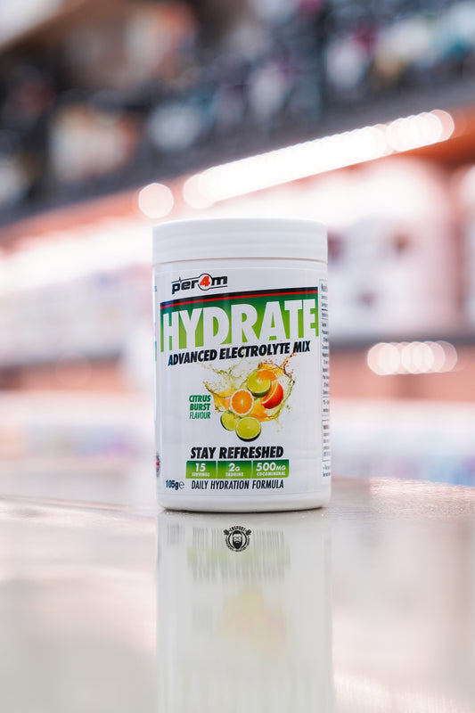 Per4m Hydrate Advanced Electrolyte Mix in Citrus Burst flavour, featuring 2g taurine, CocoMineral®, 15 servings and a daily hydration formula, displayed on a supplement store counter.
