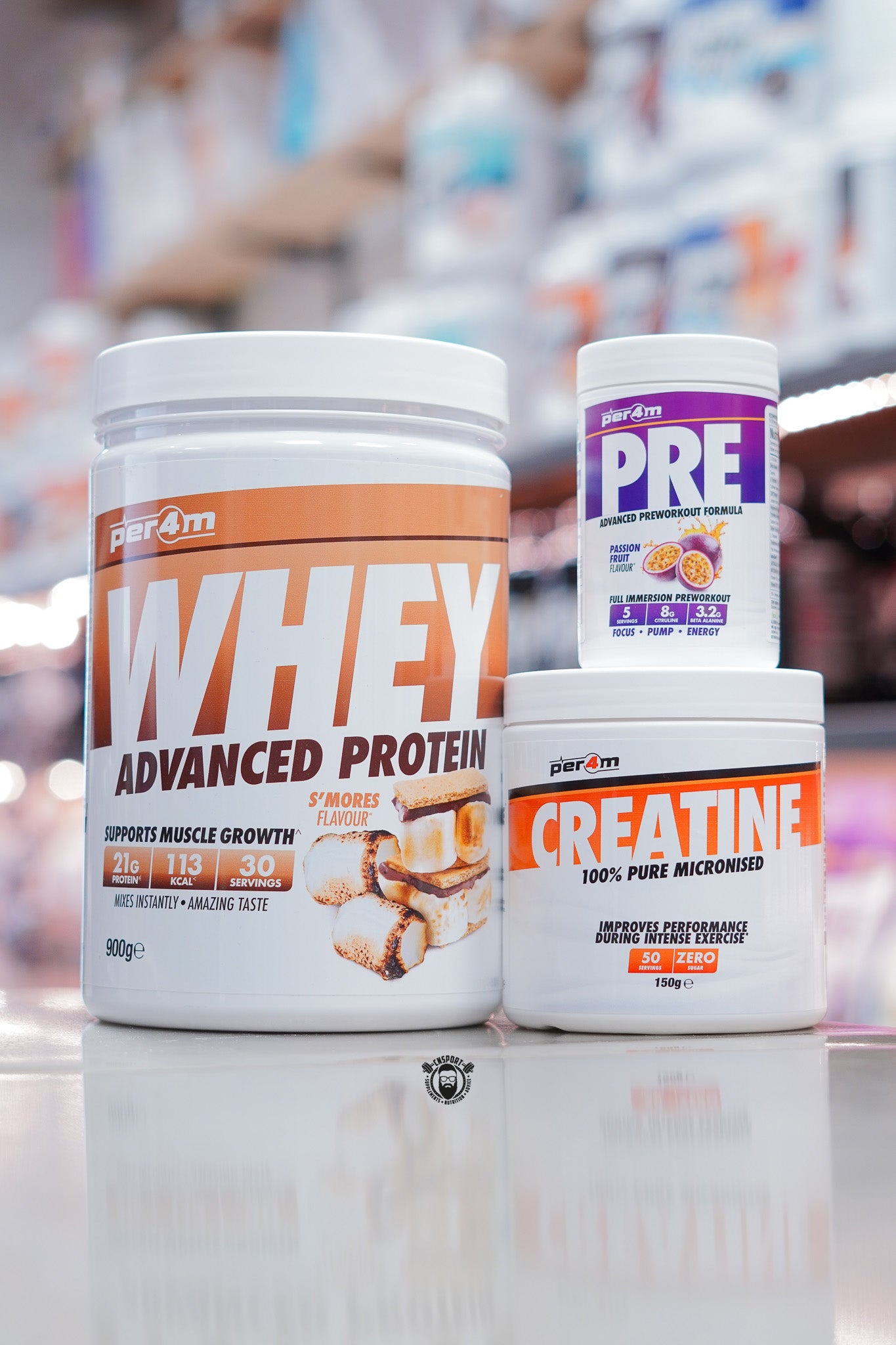 Per4m supplement bundle featuring 900g Whey Advanced Protein S’mores flavour (30 servings), Creatine Monohydrate 150g (50 servings), and Pre Advanced Pre-Workout Passion Fruit flavour, displayed on supplement store counter.