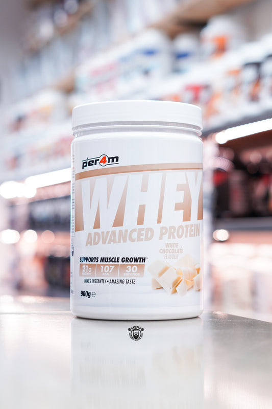 Per4m Whey Advanced Protein powder tub, White Chocolate flavour, 900g, displayed on supplement store counter.