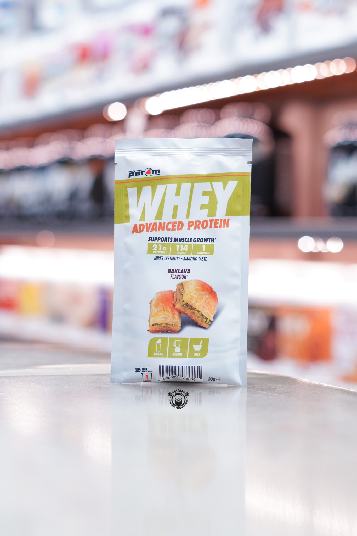 Front of a Per4m Whey Advanced Protein sample pouch in Baklava flavour, showing 21g protein, 114 kcal, and 1 serving. Image includes visual of baklava dessert and shake/blend/mix icons.