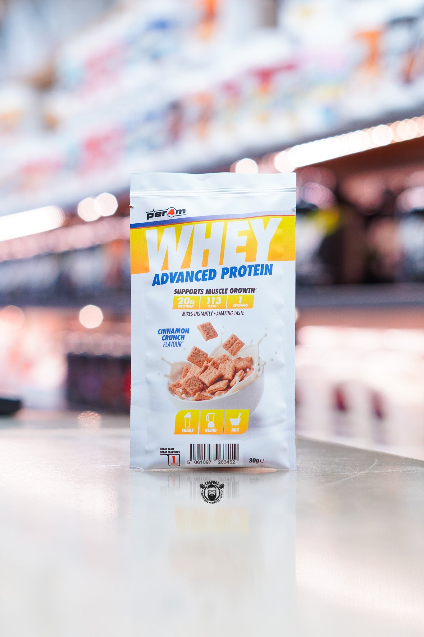 Per4m Advanced Whey Protein sample sachet, Cinnamon Crunch flavour, displayed on supplement store counter.