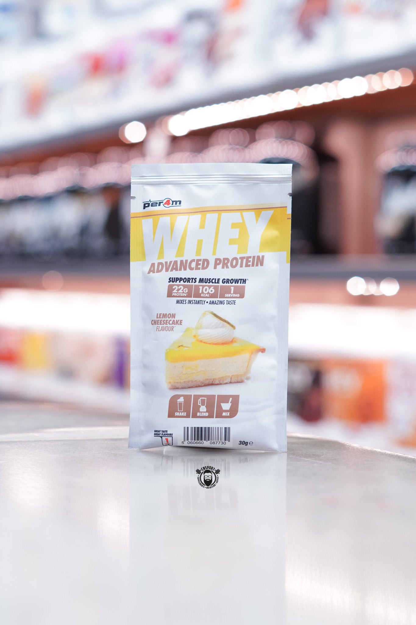 Front of a Per4m Whey Advanced Protein sample pouch in Lemon Cheesecake flavour, showing 22g protein, 106 kcal, and 1 serving. Displays lemon cheesecake image and brown shake/blend/mix icons.