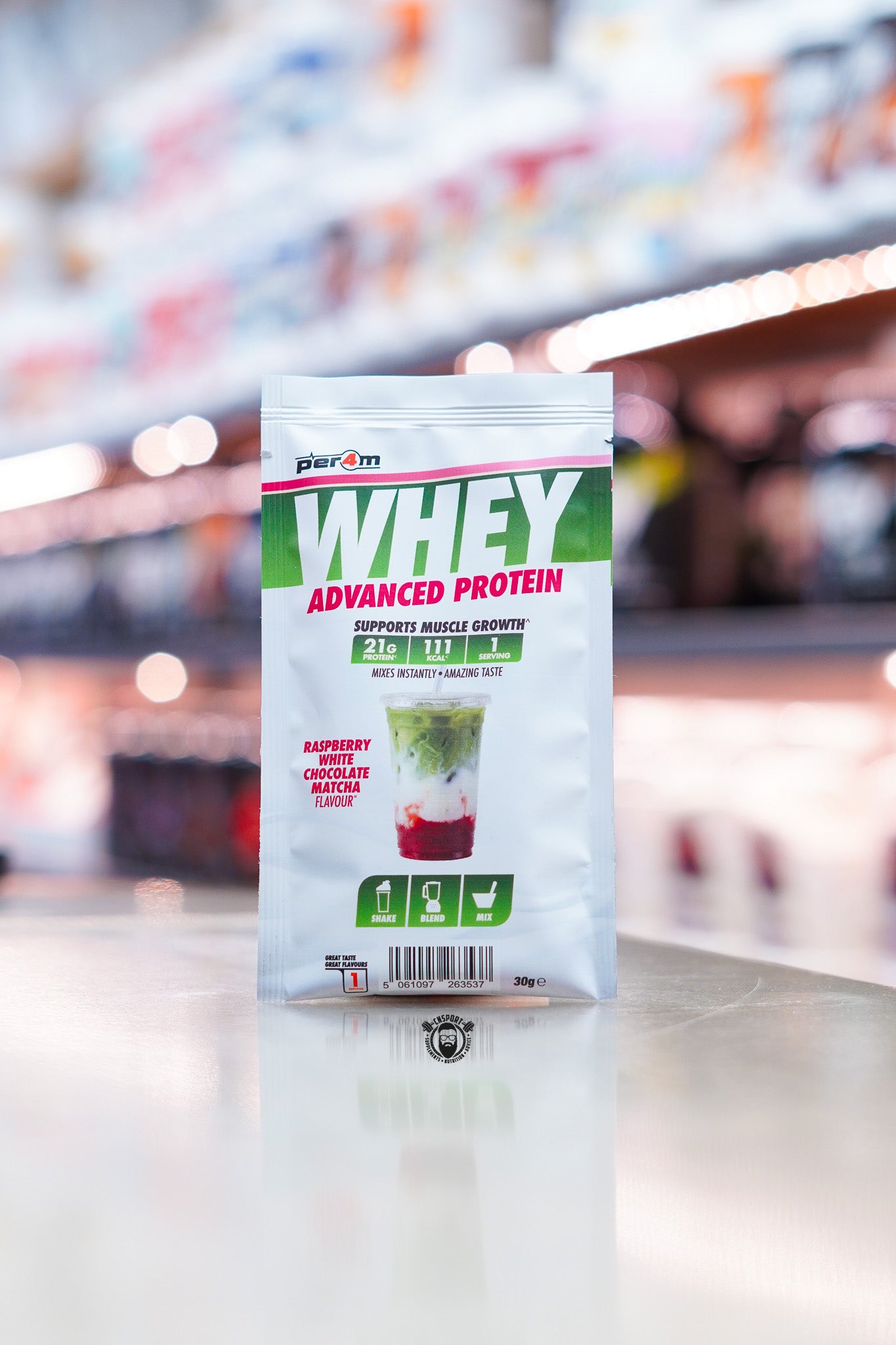 Per4m Advanced Whey Protein sample sachet, Raspberry White Chocolate Matcha flavour, displayed on supplement store counter.
