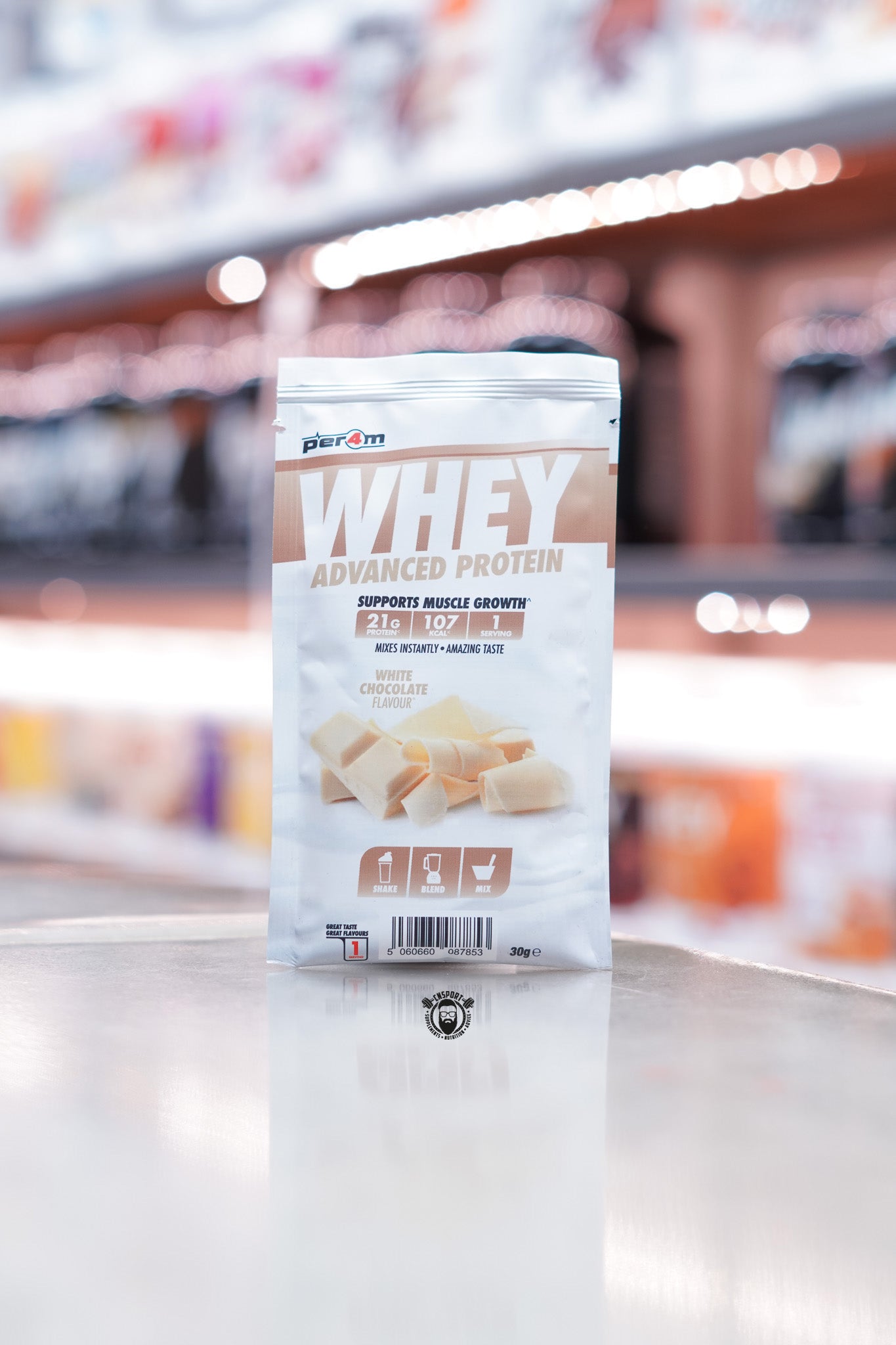 Front of a Per4m Whey Advanced Protein sample pouch in White Chocolate flavour, showing 21g protein, 107 kcal, and 1 serving. Features white chocolate curls and brown shake/blend/mix icons.
