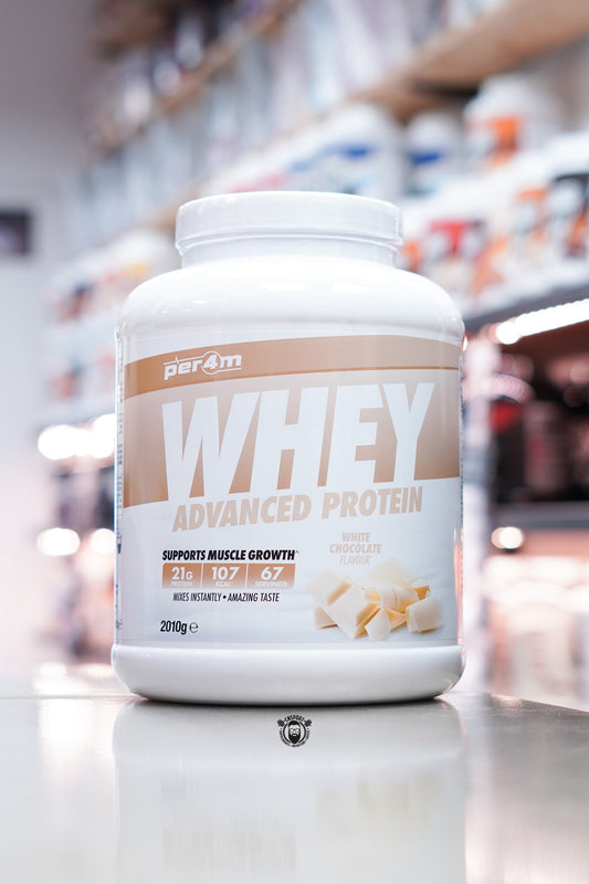 Per4m Whey Advanced Protein powder tub, White Chocolate flavour, 2kg, displayed on supplement store counter.