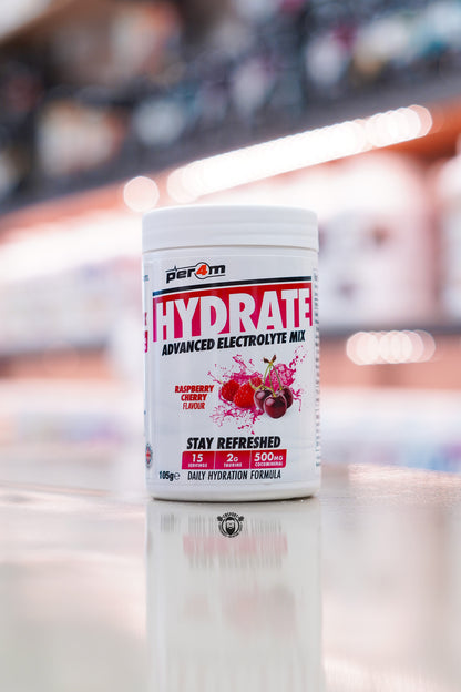 Per4m Hydrate Advanced Electrolyte Mix in Raspberry Cherry flavour, featuring 2g taurine, CocoMineral®, 15 servings and a daily hydration formula, displayed on a supplement store counter.