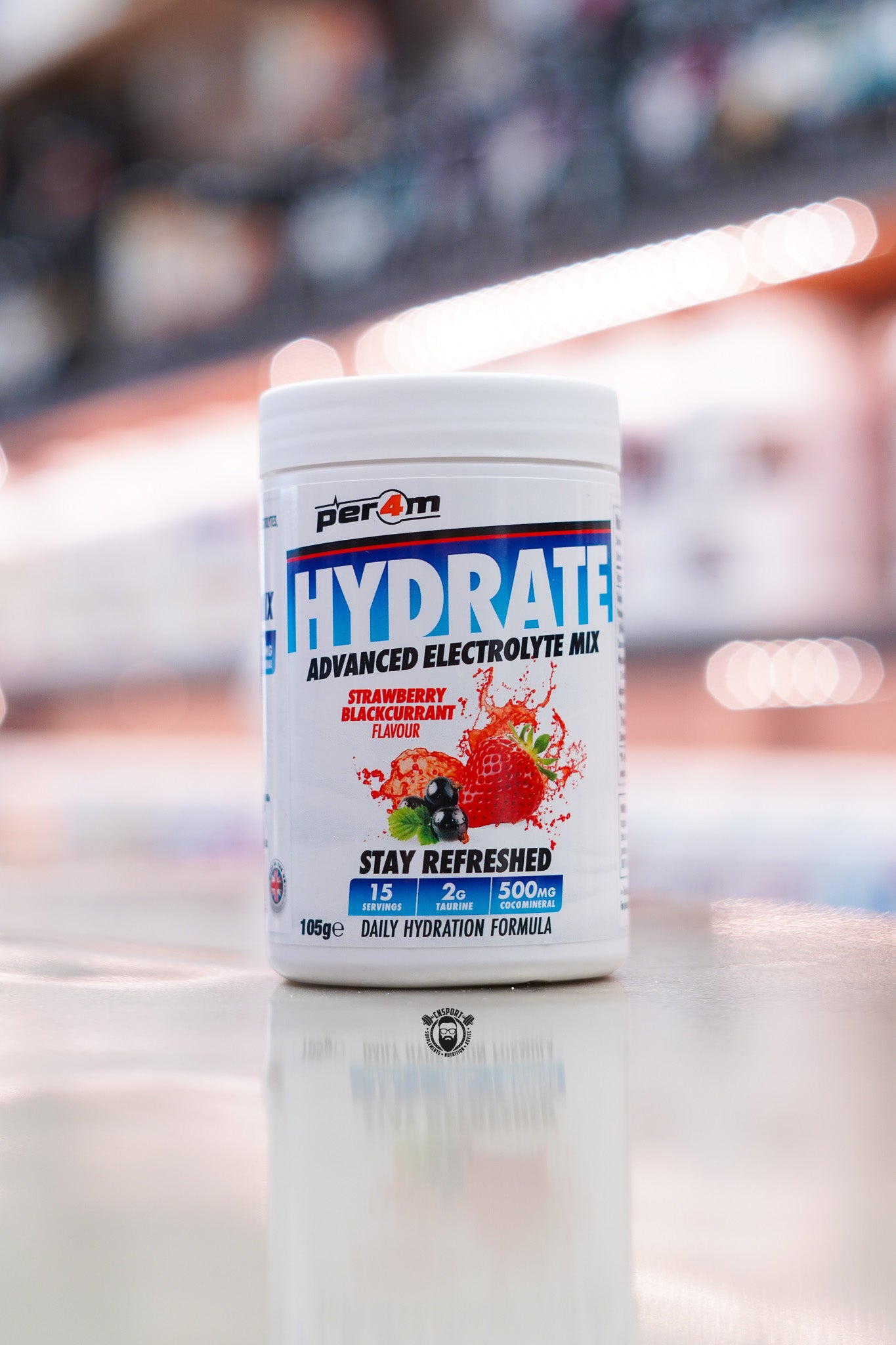 Per4m Hydrate Advanced Electrolyte Mix in Strawberry Blackcurrant flavour, featuring 2g taurine, CocoMineral®, 15 servings and a daily hydration formula, displayed on a supplement store counter.